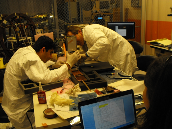 Students working on the construction of microsatellite in lab wearing lab coats and gloves