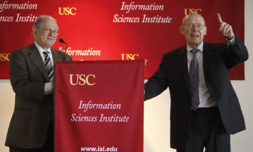 Two people standing in front of podium with USC Information Sciences Institute decorations