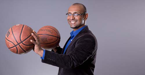 Rajiv Maheswaren wearing a suit holding basketballs in his hands