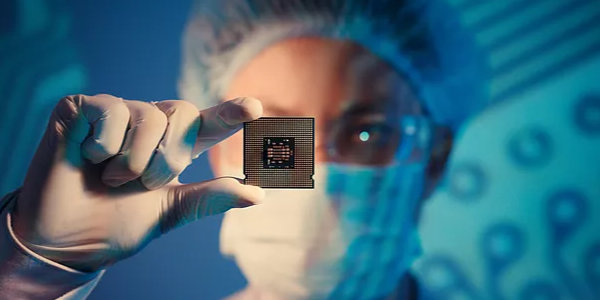 Researcher holding microchip in their hand wearing protective equiment