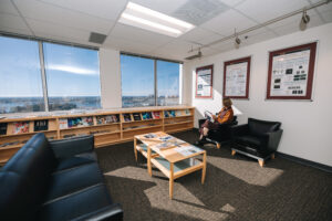 Person seated on couch in office lobby reading journal