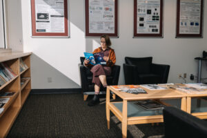 Person seated on couch in office lobby reading journal