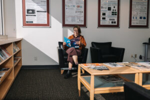 Person seated on couch in office lobby reading journal